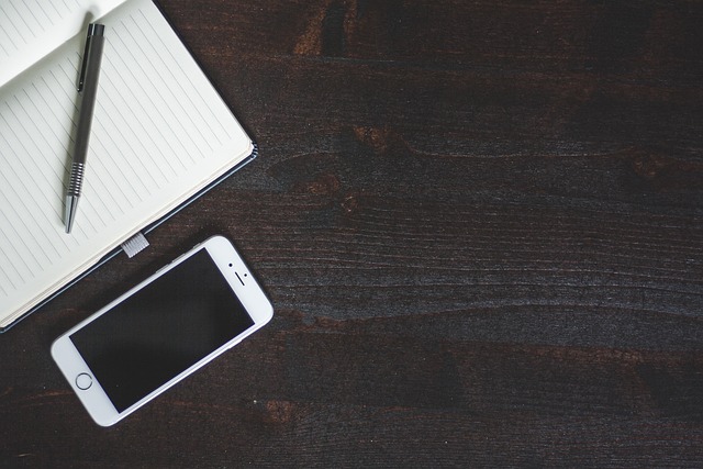 A notebook, pen, and smartphone on a wooden table