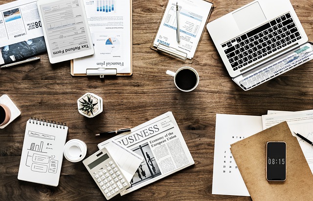 A workspace with a laptop, papers, and a cup of coffee, symbolizing the development of a marketing research plan